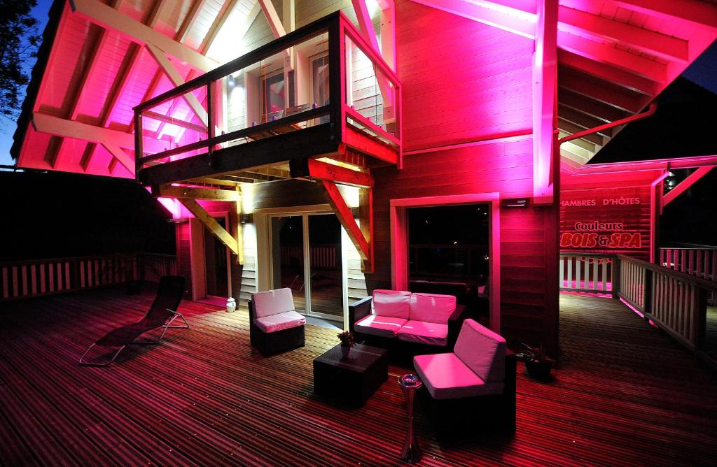 a house with pink lighting on a deck at Chambres d'hôtes Couleurs Bois & Spa in Xonrupt-Longemer