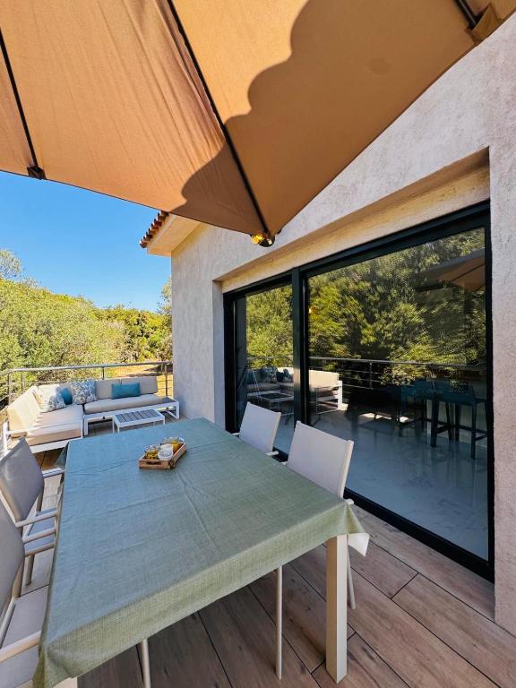 une salle à manger avec une table et des chaises sur un patio dans l'établissement Appartement paisible au cœur des oliviers, à deux pas de Bonifacio, à Bonifacio
