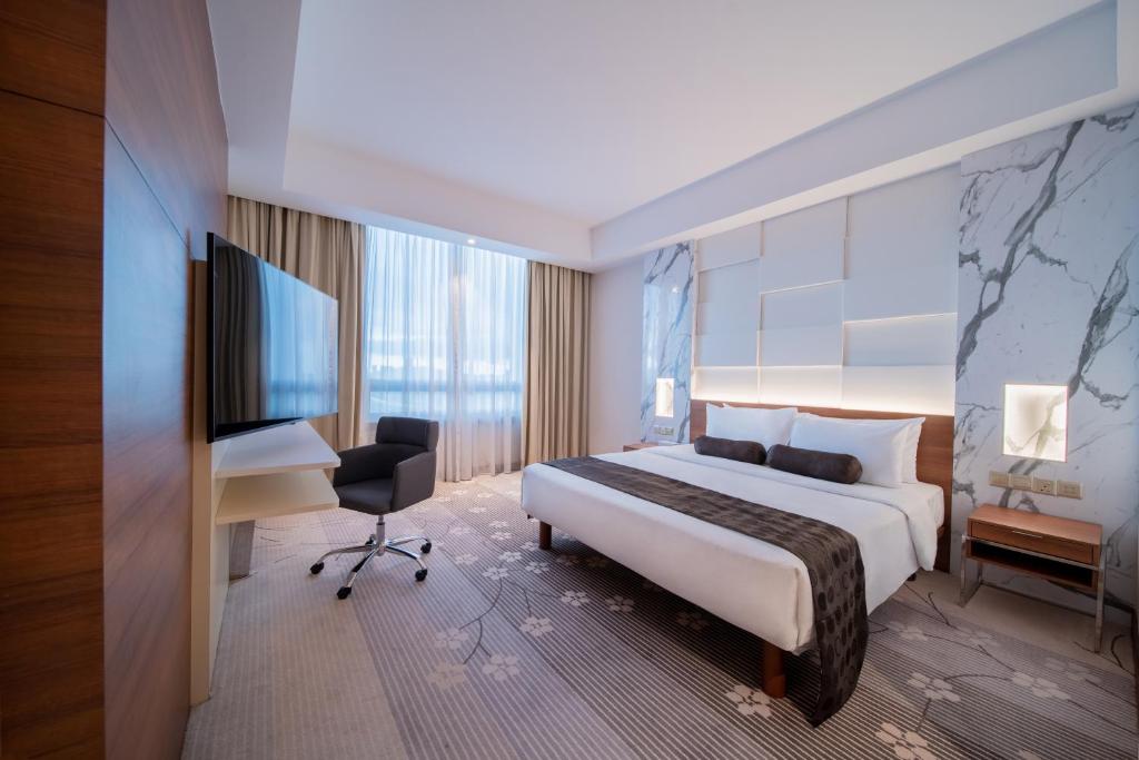 A polished hotel bedroom with a king-size bed, window seating and a compact work desk.