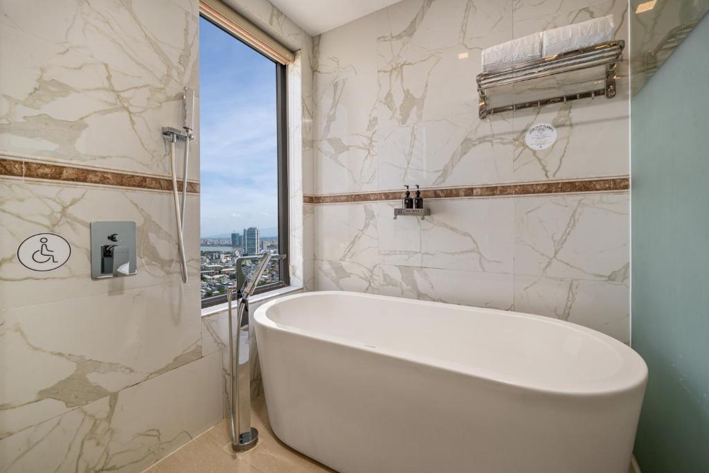A marble-look bathroom with a freestanding bathtub beside a city-view window.