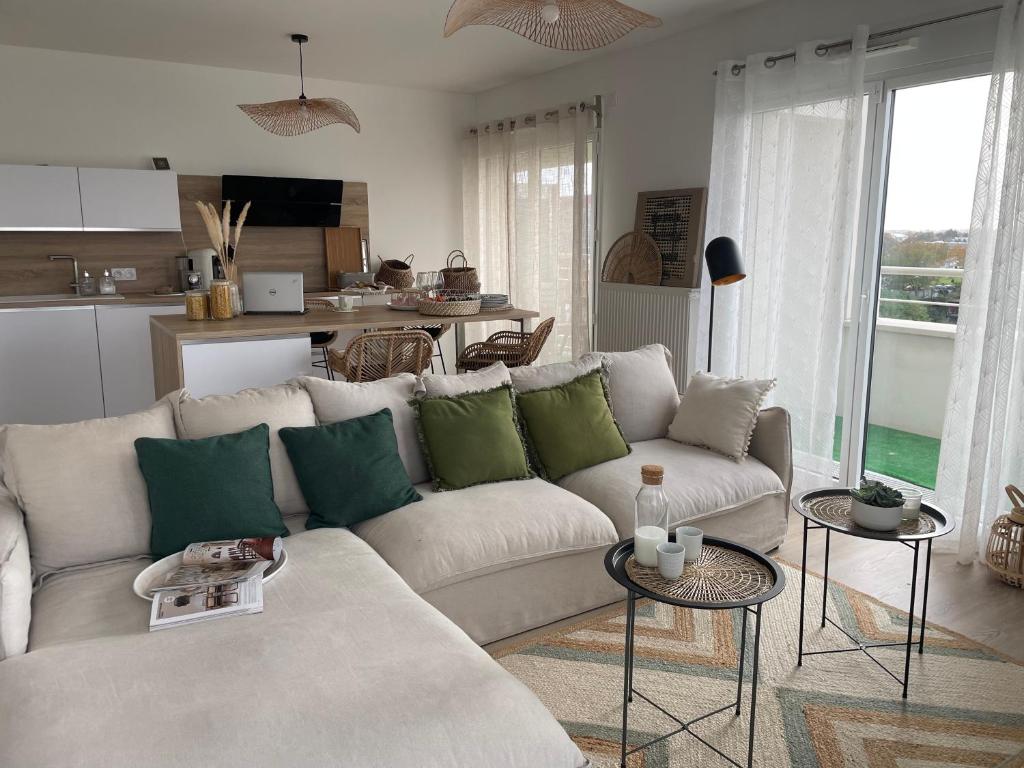 a living room with a white couch and green pillows at Bienvenue chez nous in Noisy-le-Grand