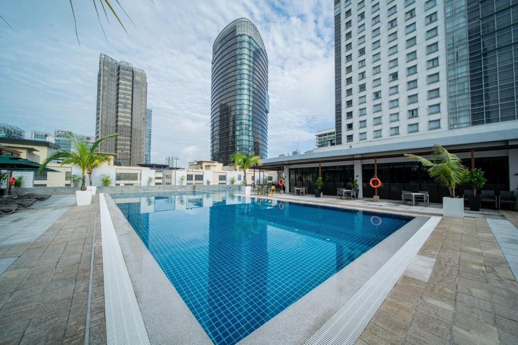 A rooftop-style outdoor pool surrounded by city towers and a paved deck.