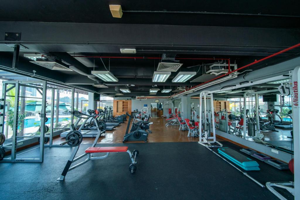 A large mirrored fitness room with cardio machines, weights, and gym benches.