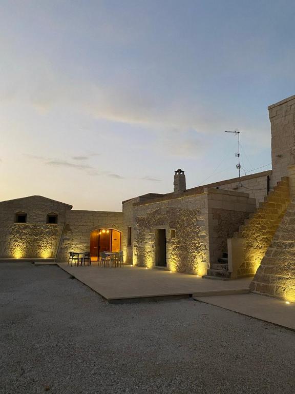 a stone building with a patio with lights on it at Agriturismo Masseria Sbotta in SantʼAndrea