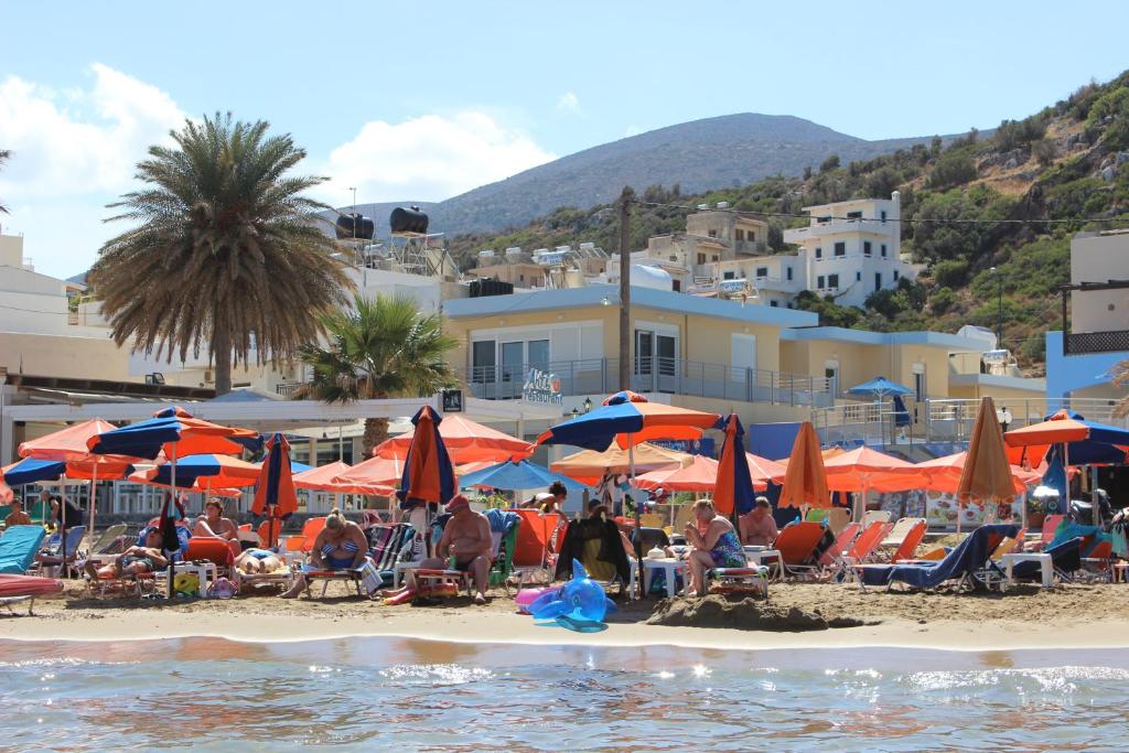 een groep mensen op een strand met parasols bij 4S Beach Superior Apartments in Stalida