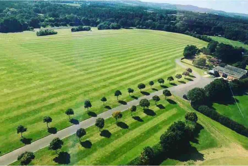 an aerial view of a field with trees and a road at Picturebook cottage on prestigious polo estate in Stedham
