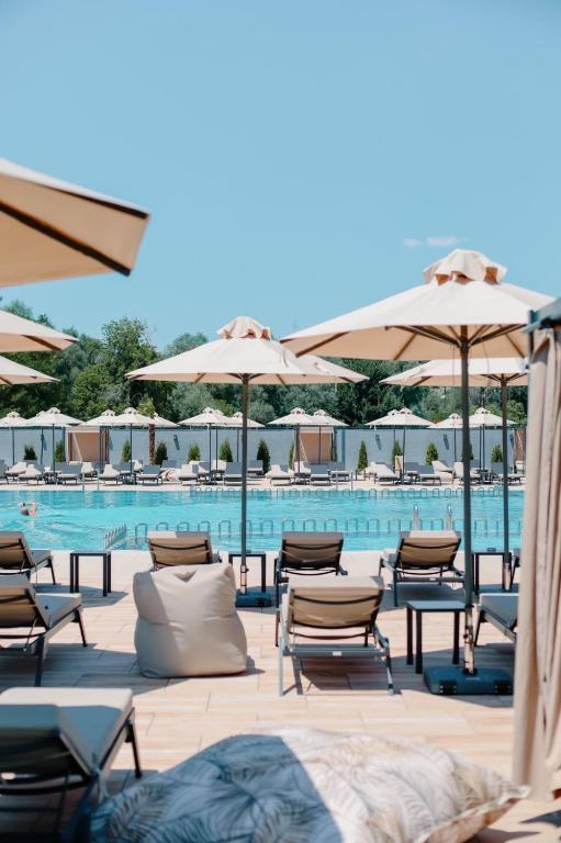 a pool with tables and chairs and umbrellas at Coconut Hotel And Pool in Gevgelija