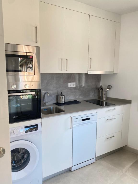 a kitchen with white cabinets and a washing machine at Mundaka plaza in Mundaka