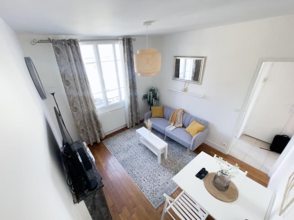 a living room with a couch and a table at Le Cocon Raffiné in Bagneux