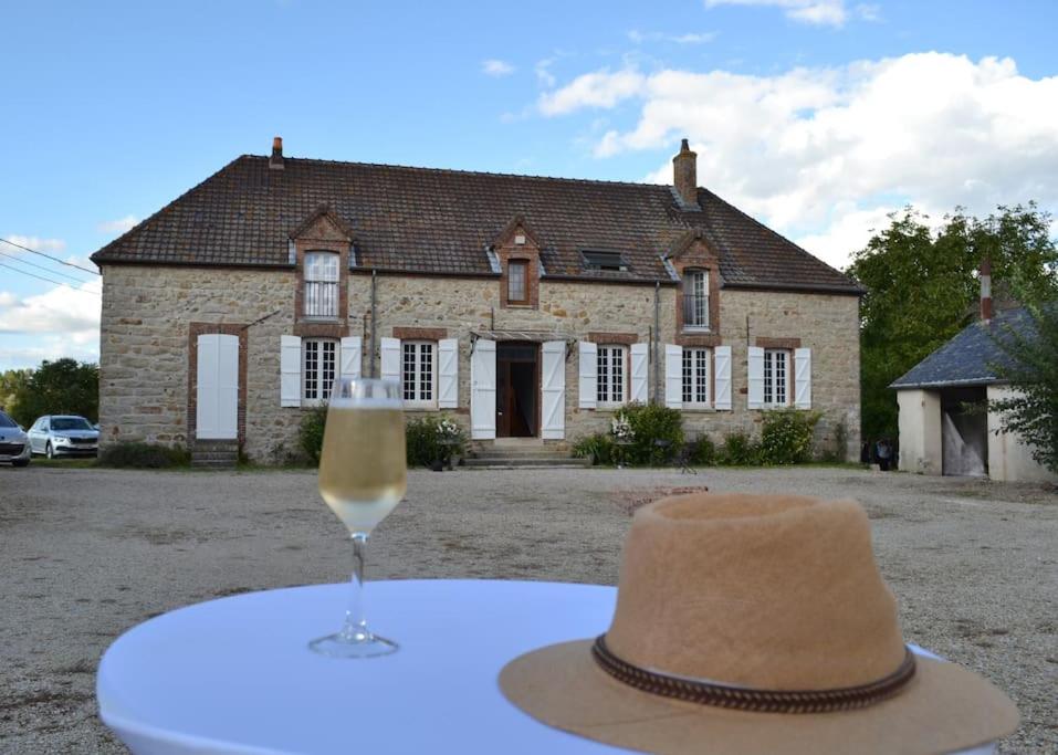 a hat and a glass of wine on a table in front of a house at Le Clos du Hayer in Bercenay-le-Hayer