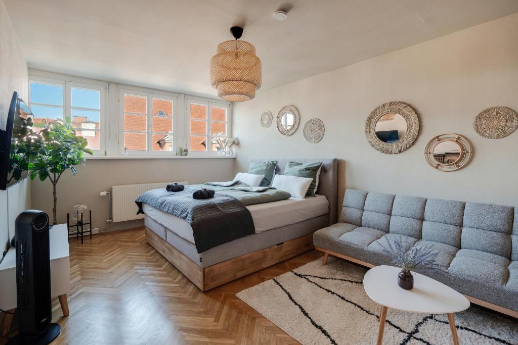 a bedroom with a bed and a couch at Boho Design Studio - Historic City Center with Free Parking & AirCon by HERO HOMES in Graz