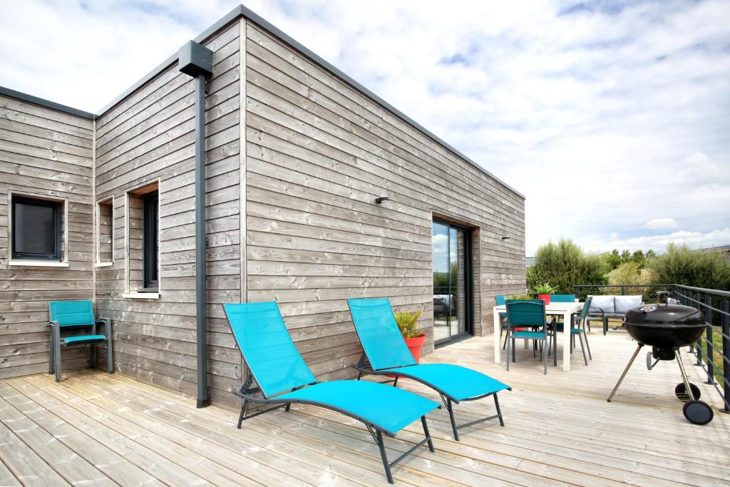 une terrasse avec des chaises bleues et un grill dans l'établissement L'Harmonie - A 5min de la plage, à Les Moitiers-dʼAllonne