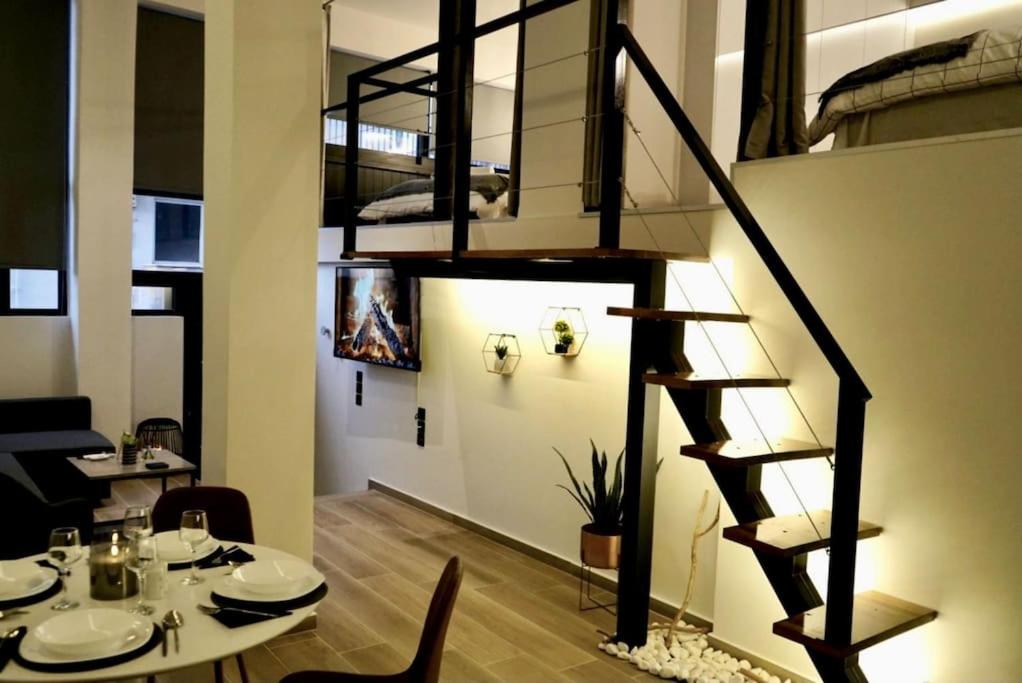 a dining room with a table and a spiral staircase at Cosy Loft in Patra