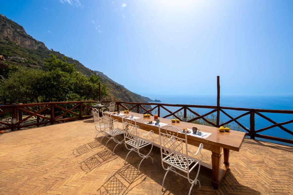 a wooden table and chairs on a balcony with the ocean at Casa Allegra in Praiano