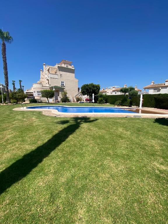 a large yard with a swimming pool in front of a house at Apartament Villamartin Tosca Golf-Pool in Orihuela Costa
