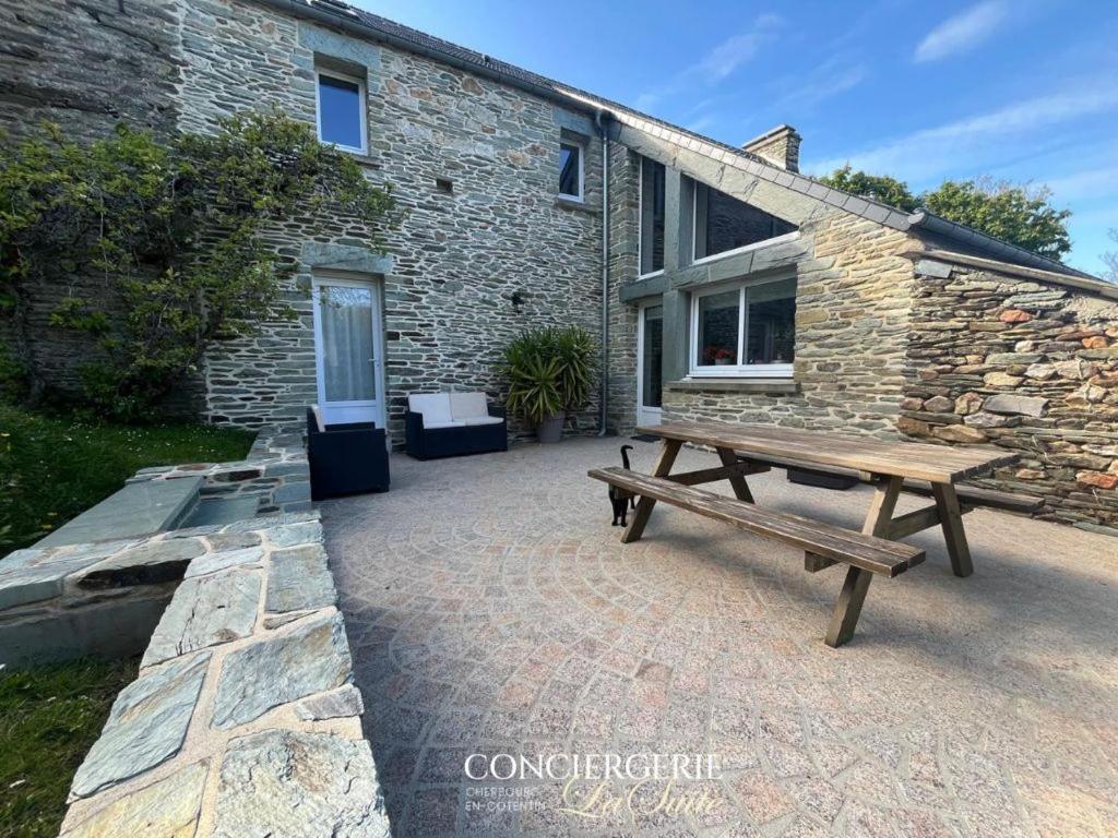 un banc en bois assis à l'extérieur d'un bâtiment en pierre dans l'établissement La croix Luce, à Cherbourg en Cotentin