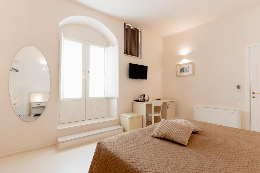 a white bedroom with a bed and a mirror at Il Belvedere in Matera