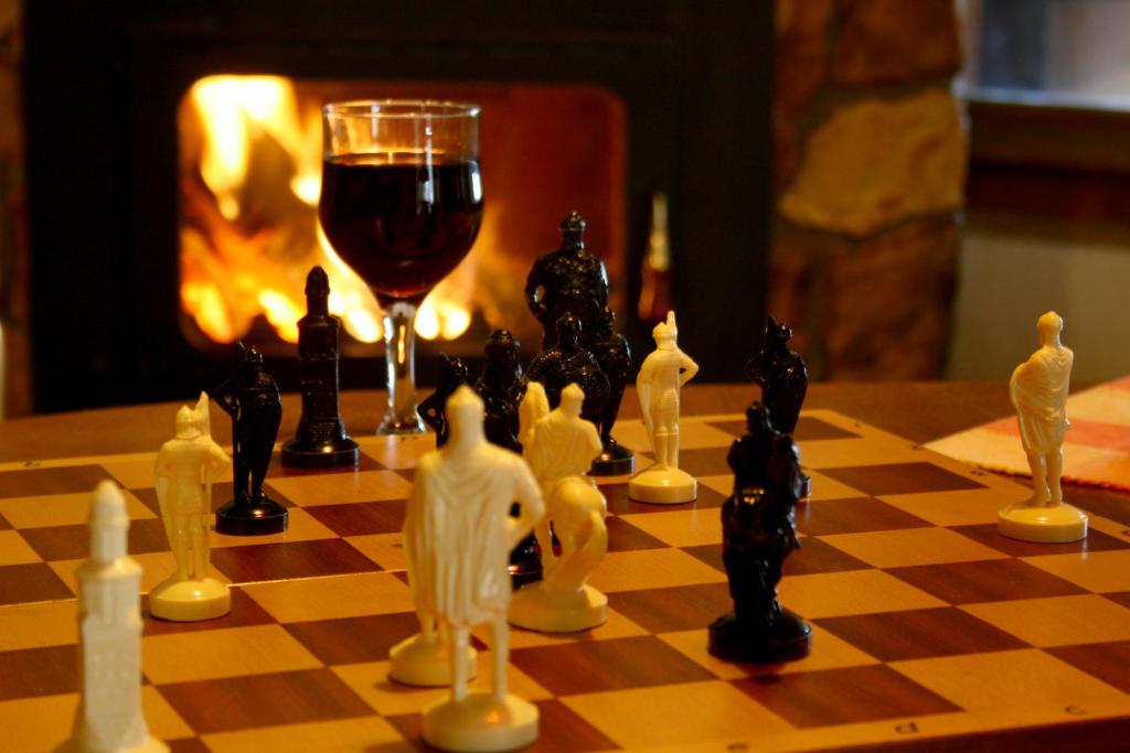 a chess board with a glass of wine and chess pieces at Guesthouse KaraIvan in Arda