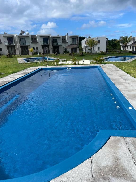 a large blue swimming pool with houses in the background at VILLA cHELSEA 2 bed room in Grand Gaube