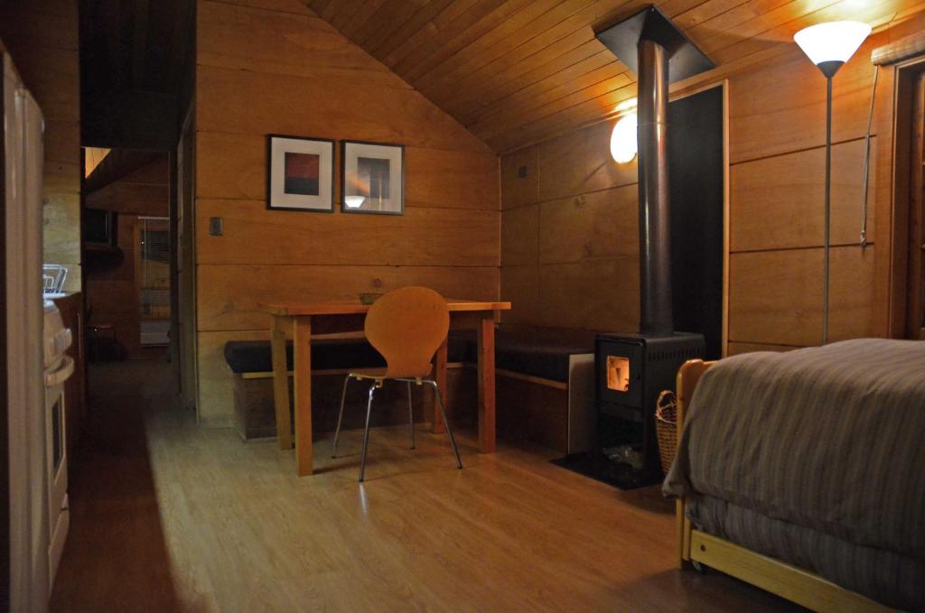 a bedroom with a table and a bed and a room with a fireplace at Palafito Azul Apart Hotel in Castro