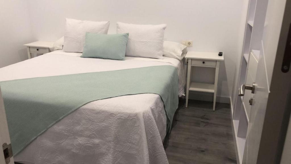 Cama con manta y almohadas verdes y blancas en Luz de Mar, en O Grove
