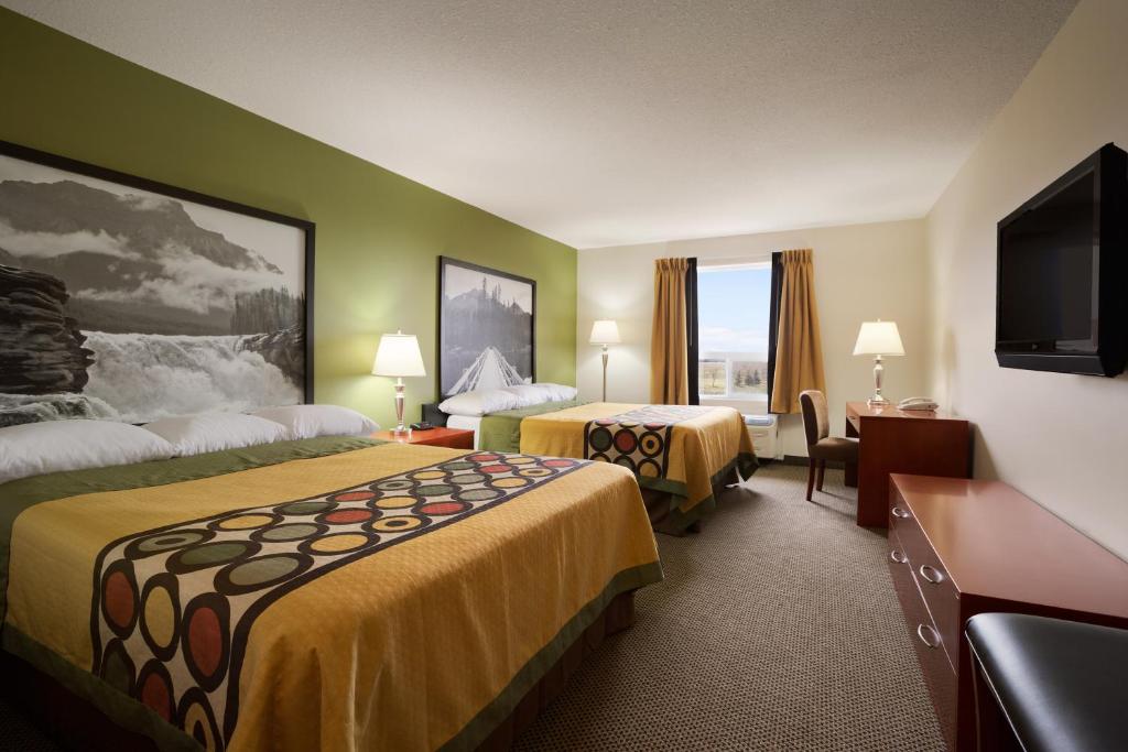 a hotel room with two beds and a flat screen tv at Super 8 by Wyndham Sherwood Park/Edmonton Area in Sherwood Park