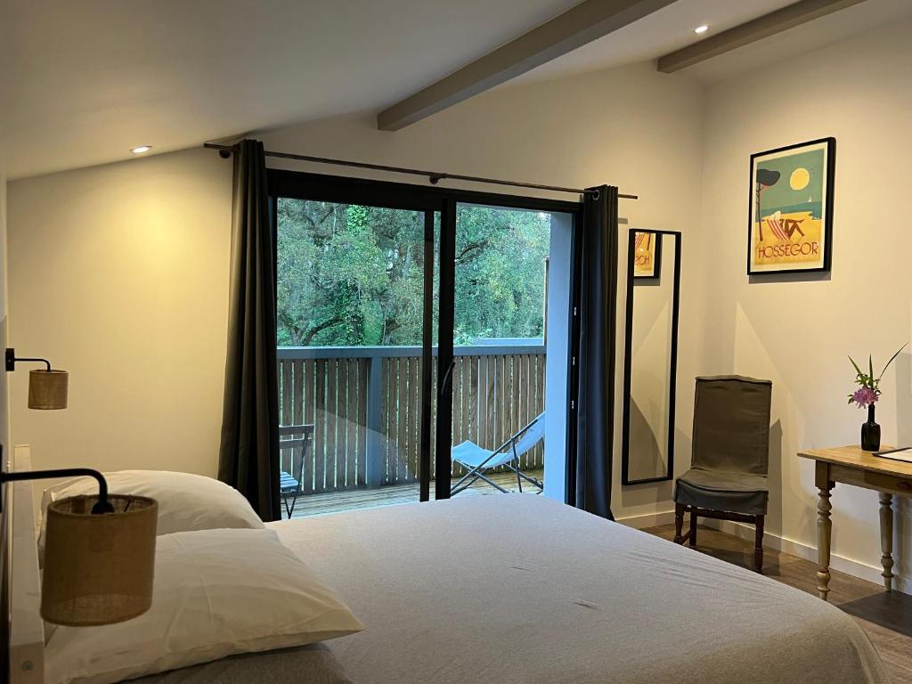 a bedroom with a bed and a sliding glass door at Laguillotte in Seignosse