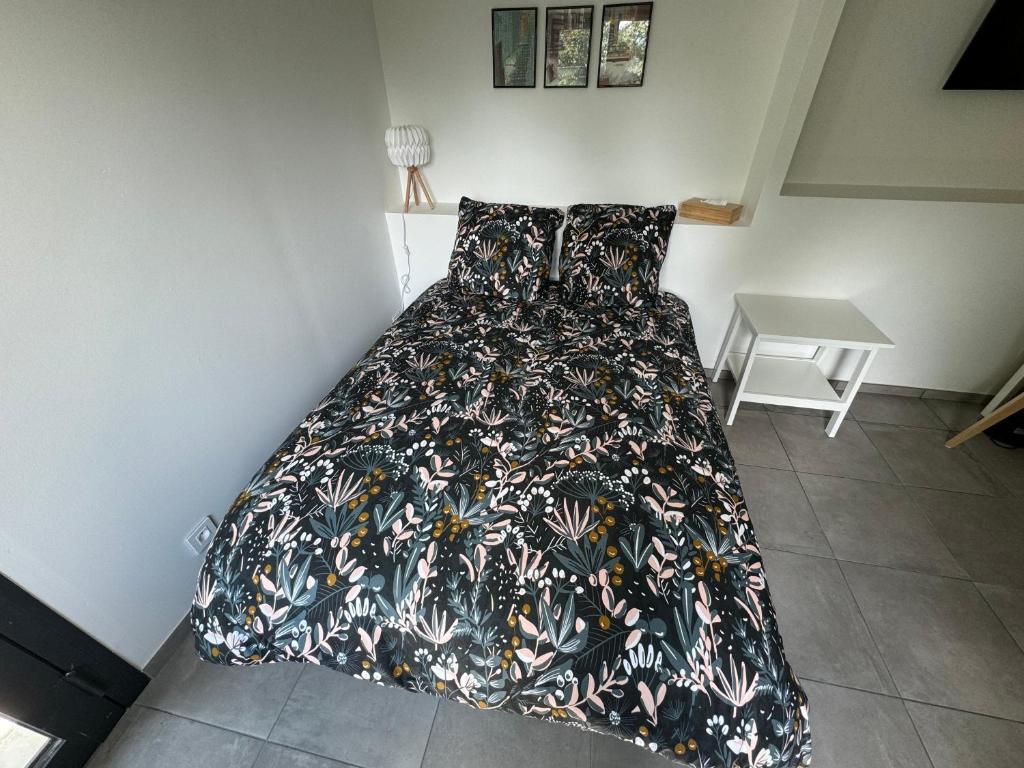 a bed with a blanket on it in a room at Studio neuf rez de jardin dans chalet individuel in Thollon