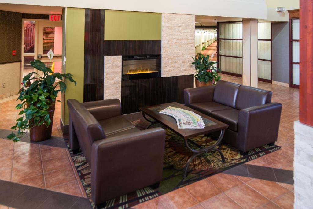 a lobby with two chairs and a table and a fireplace at Super 8 by Wyndham Sherwood Park/Edmonton Area in Sherwood Park