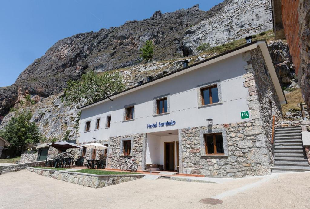 a building with a mountain in the background at Hotel Rural Somiedo in Valle de Lago