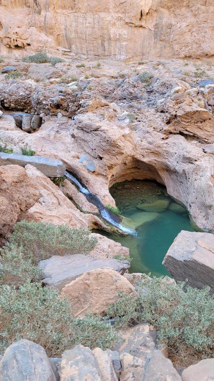 a pool of water in a canyon with rocks at Tigmi Bulbul in Id AÃ¯ssa