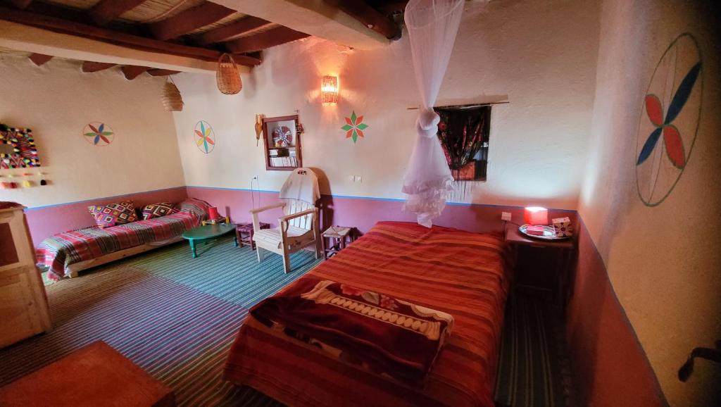 a bedroom with a red bed and a living room at Tigmi Bulbul in Id AÃ¯ssa