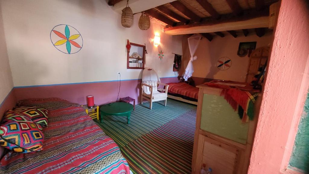 a bedroom with a bed and a table in a room at Tigmi Bulbul in Id AÃ¯ssa