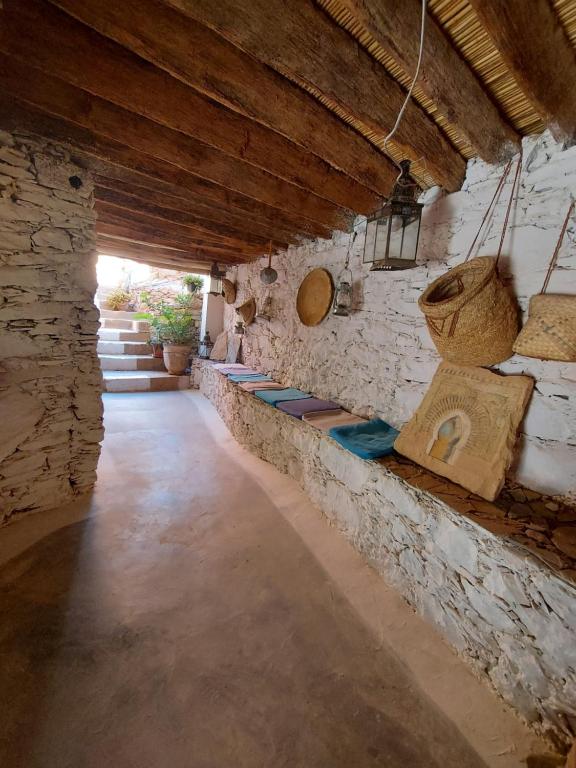 a room with a stone wall with a row of benches at Tigmi Bulbul in Id AÃ¯ssa