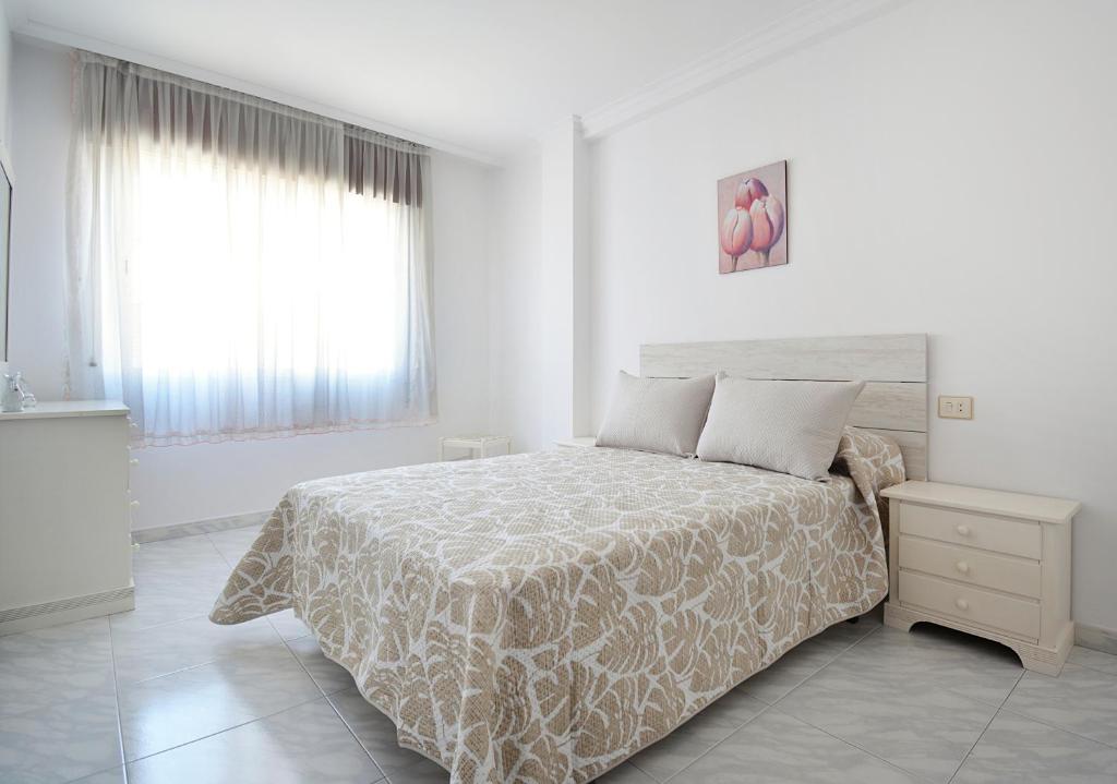 a white bedroom with a bed and a window at Enorme TRIPLEX en el centro de O Grove in O Grove