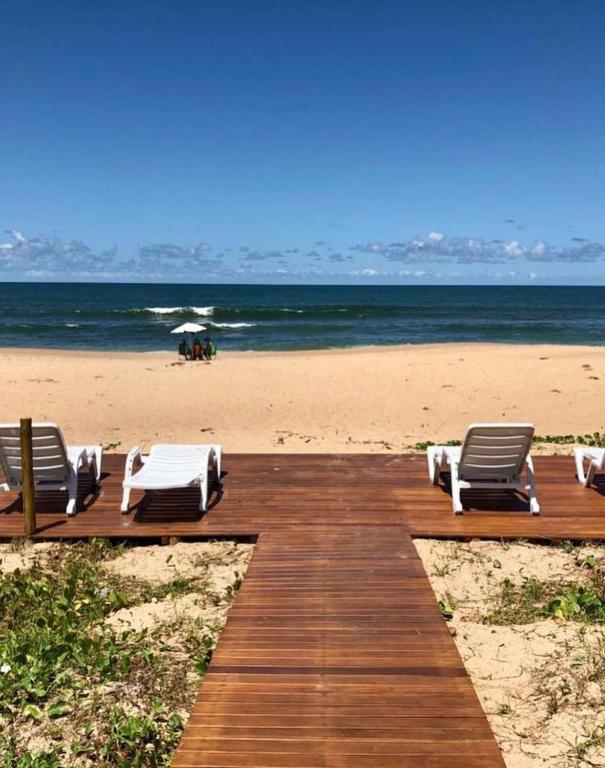 a beach with two chaise lounges on a wooden boardwalk at Imperia Lounge Itacimirim in Camacari