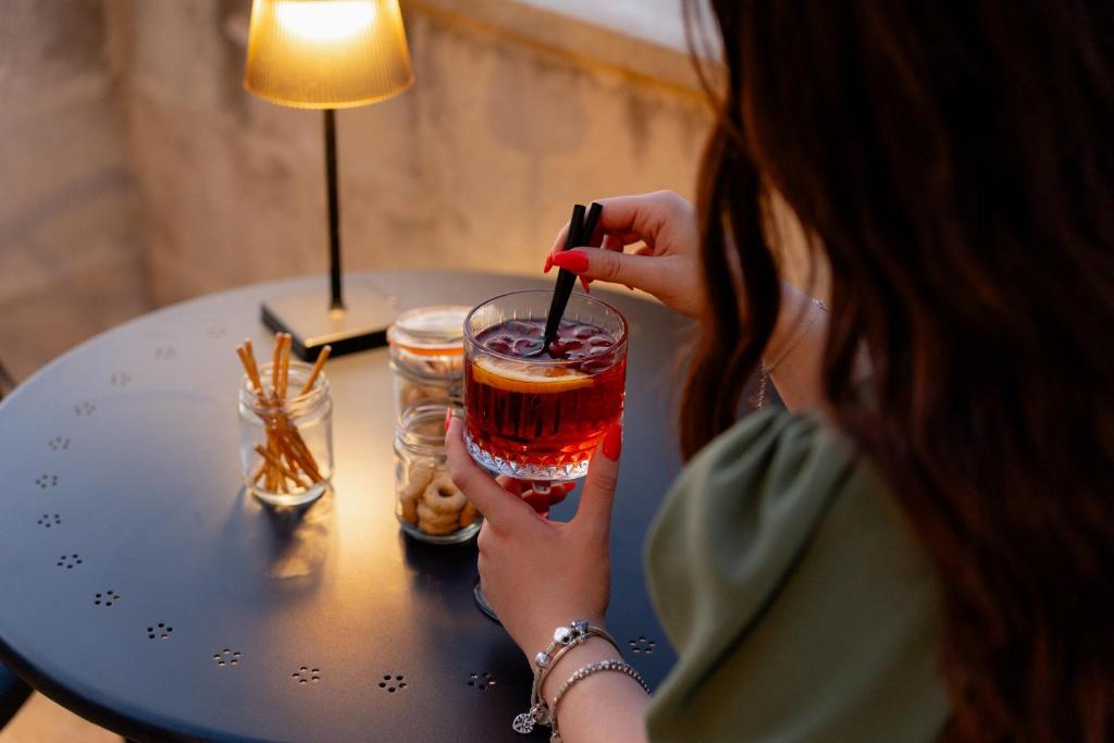 a woman sitting at a table holding a drink at Il Belvedere in Matera