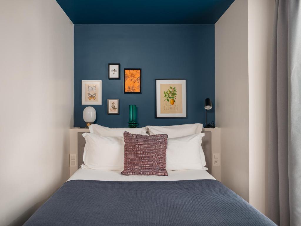 a bedroom with a bed with a blue wall at Hotel Belleval in Paris