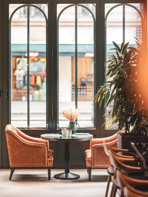 a table and chairs in a room with windows at Hotel Belleval in Paris