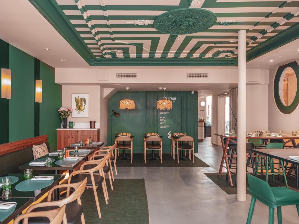 a restaurant with green walls and tables and chairs at Hotel Belleval in Paris