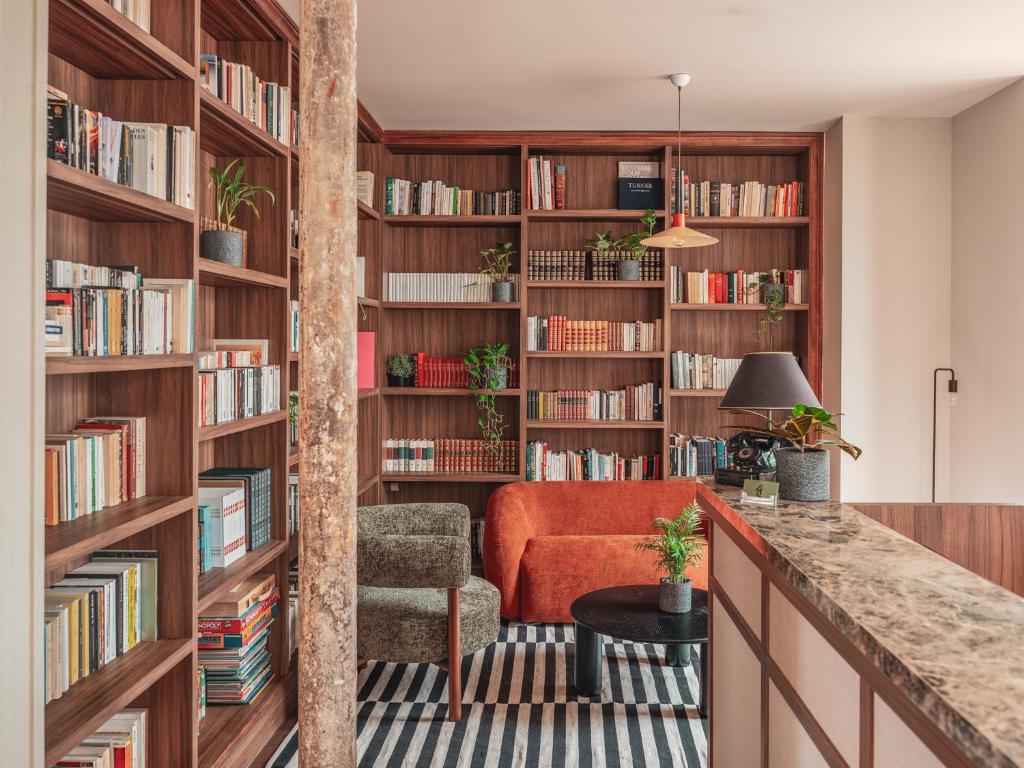 a library with wooden book shelves filled with books at Hotel Belleval in Paris