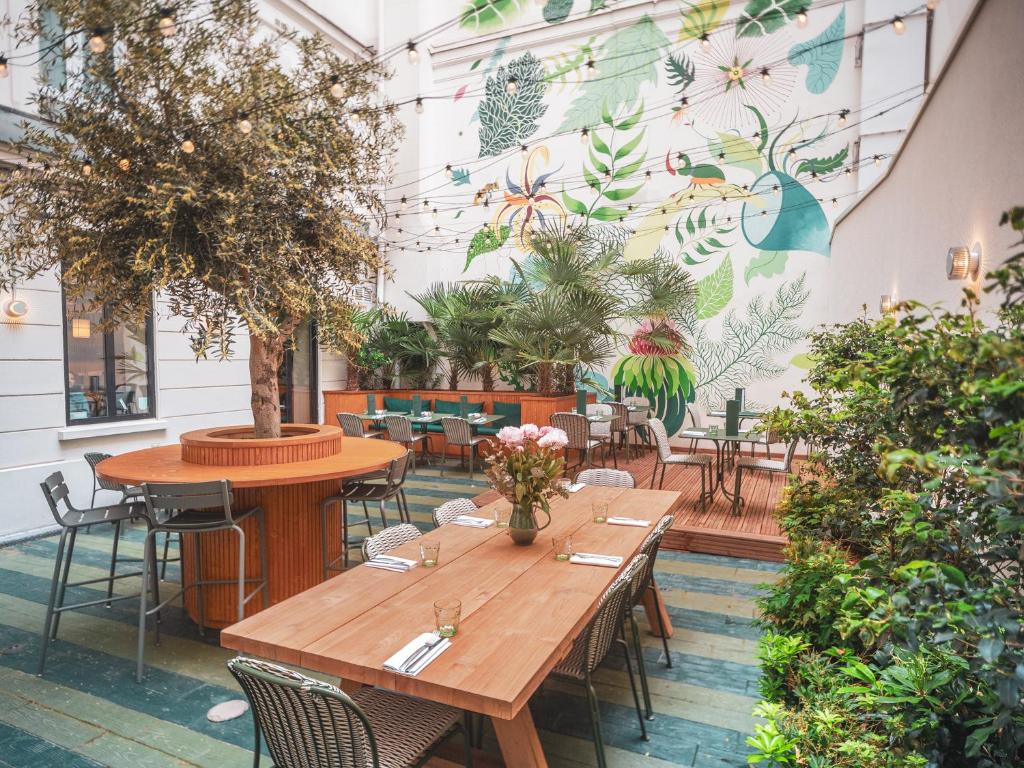 a restaurant with tables and chairs and a wall with plants at Hotel Belleval in Paris