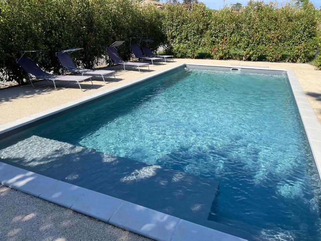 une piscine avec des chaises dans une cour dans l'établissement MAS CLEMENTINE GÎTES Appartements, à Chambonas