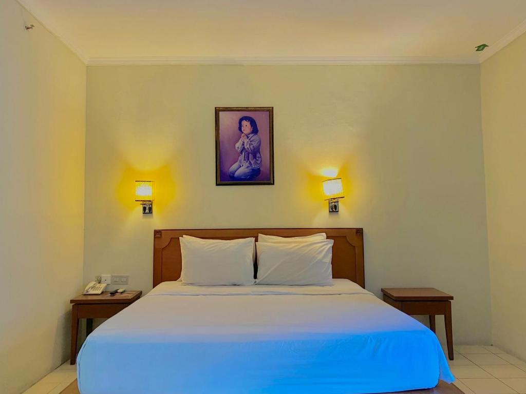 a bedroom with a large bed with a blue blanket at Pia Hotel in Cirebon