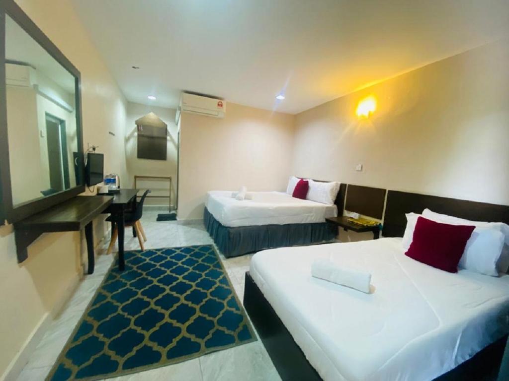 a hotel room with two beds and a desk at Motel Seri Mutiara in Kuah