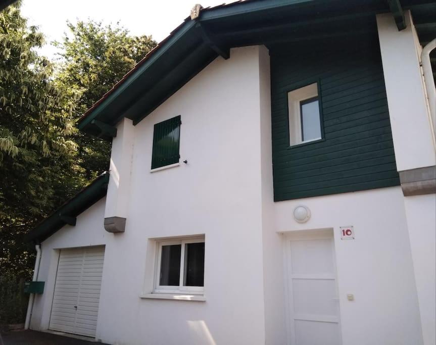 une maison blanche avec un toit vert dans l'établissement Maison pavillonnaire entre océan et montagnes basques, à Cambo-les-Bains