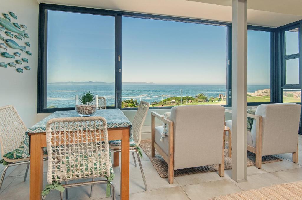 a dining room with a view of the ocean at Walker Bay Luxury Seafront Apartment in Hermanus