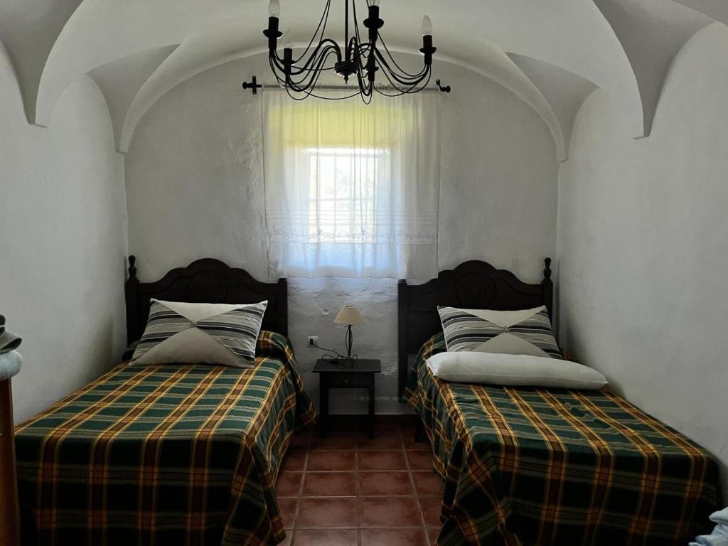 a bedroom with two beds and a chandelier at Casa Rural Cortijo Torres in La Parra