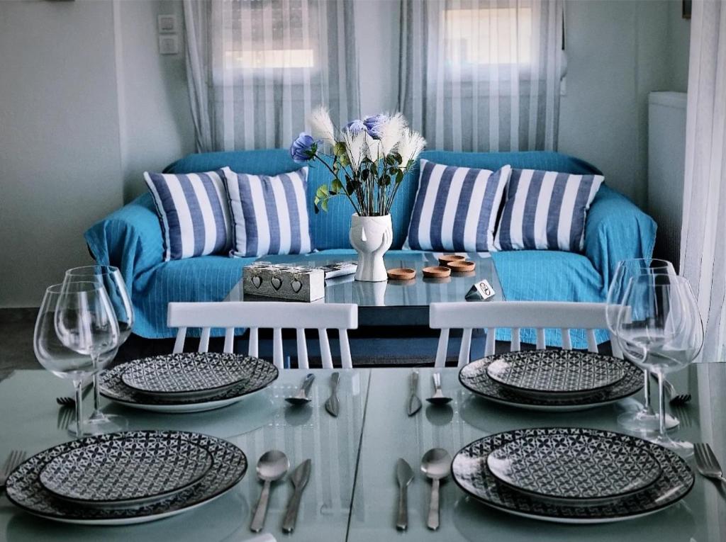 a living room with a blue couch and a glass table at Tararas apartments in Nea Michaniona