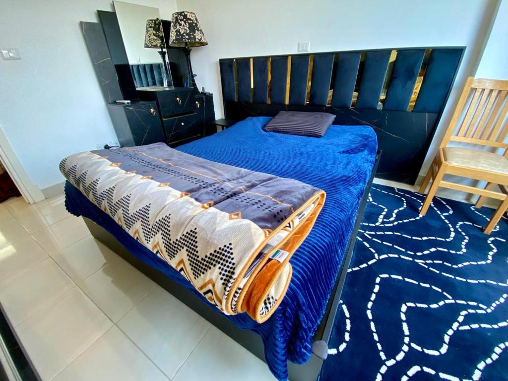 a bedroom with a bed with a blue blanket and a chair at Luxe Home in Madinaty in Madinaty